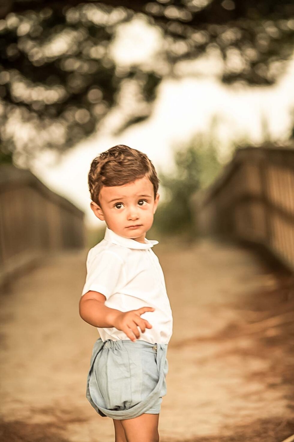 Bebé posando para una sesión de fotos en Chiclana, en un ambiente natural con un puente de madera de fondo