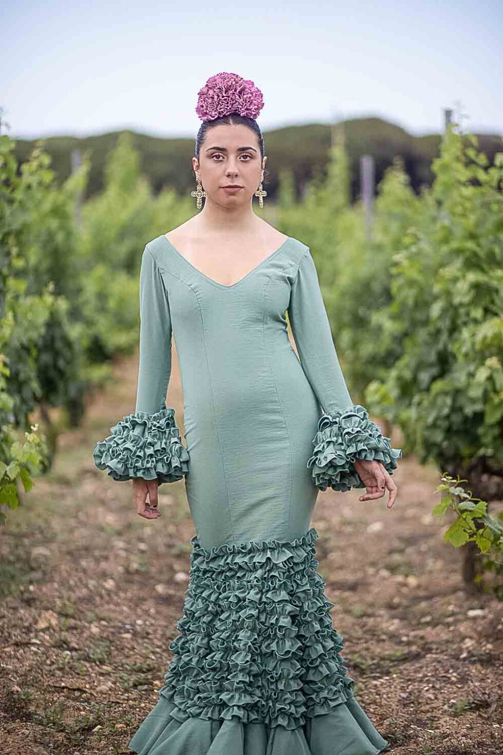 Mujer vestida de flamenca posando entre viñedos