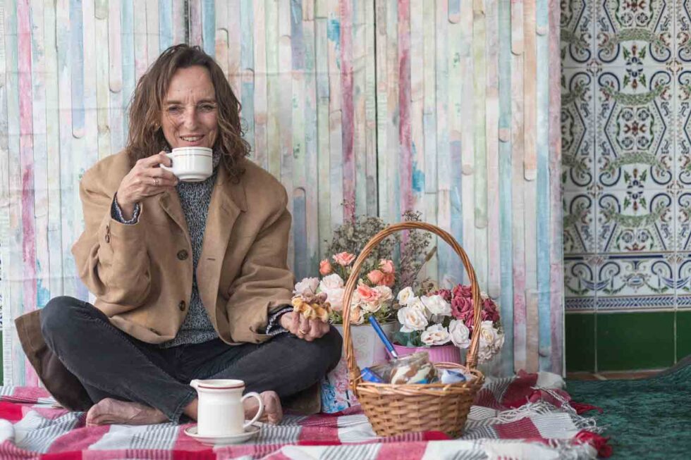 Mujer bebiendo en una taza de café en un decorado con mantel y flores
