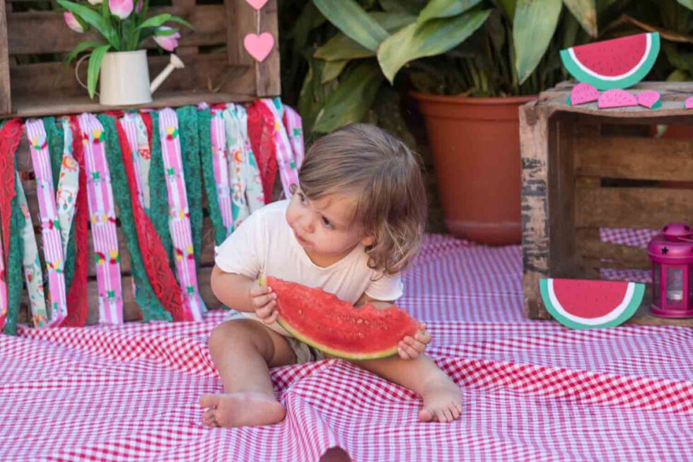 Niña pequeña sosteniendo una rodaja de Sandía en un decorado de picnic muy bonito